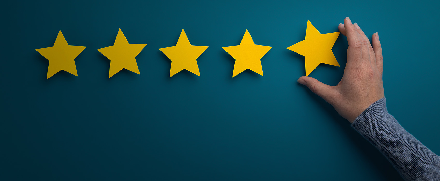 The image features a graphic of five yellow stars on a blue background, with a hand holding the first star and seemingly placing it onto the wall.