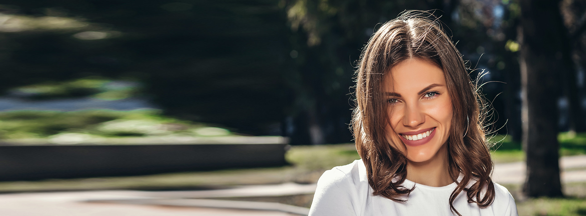 A woman with blonde hair, smiling and standing outdoors.